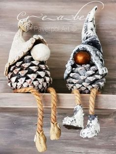 two small pine cones are hanging on a shelf with rope and wood balls attached to them