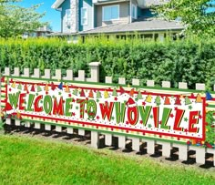 a welcome sign on a fence in front of a house