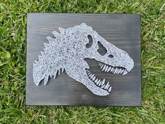 a paper cut out of a dinosaur's head on top of some green grass