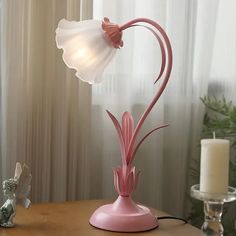 a pink lamp on a table next to a candle