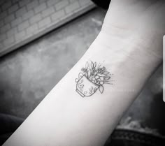 a black and white photo of a wrist tattoo with flowers on the left side of it