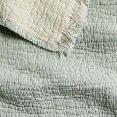 an unmade bed with green and white bedspread