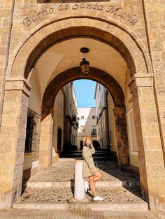 a woman sitting on the steps in front of an archway