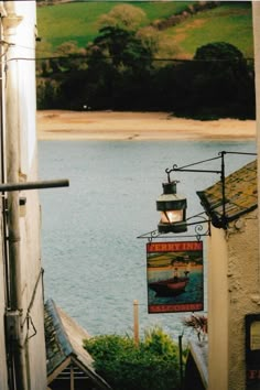 a sign hanging from the side of a building next to a body of blue water