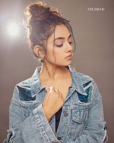 a woman wearing a jean jacket with her hands on her chest