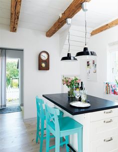 a kitchen with two blue chairs and a black counter top next to a clock on the wall