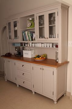 a kitchen with white cabinets and wooden counter tops, along with a bowl of fruit on the counter