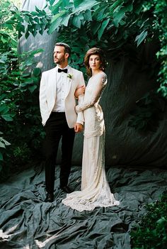 a man and woman dressed in formal wear standing next to each other on a black cloth covered ground