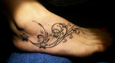 a foot tattoo with stars and swirls on it