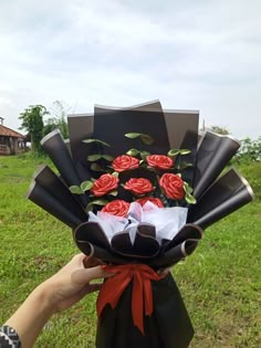 a person is holding a bouquet of roses in their hand and it looks like they are wrapped in black paper