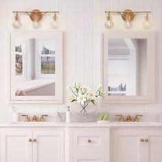 a bathroom with two sinks, mirrors and lights on the wall above them is shown