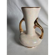 a white and gold vase sitting on top of a table