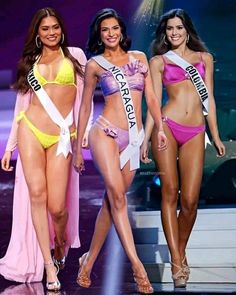 three beautiful women in bikinis walking down the runway with one woman wearing a sash