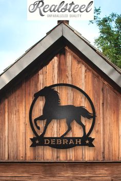 a wooden building with a metal horse sign on it's side and trees in the background