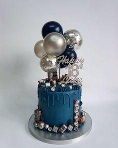 a blue birthday cake with balloons on top