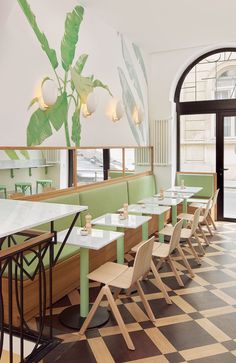 an empty restaurant with green booths and checkered flooring on the walls, along with white tables and chairs