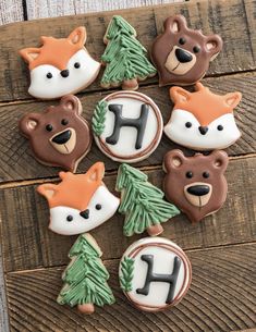 decorated cookies in the shape of animals and trees on a wooden table with wood planks