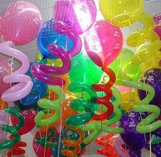 many colorful balloons are hanging from the ceiling