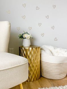 a white chair sitting next to a gold table on top of a hard wood floor