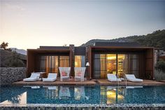 a house with a pool in front of it and some chairs on the deck next to it