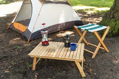 a camping table and chair set up next to a tent