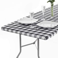 a black and white checkered table cloth with place settings for two plates on it