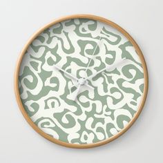 a green and white wall clock with an animal print pattern on the face, in front of a white background