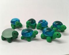 small green and blue turtle figurines sitting next to each other on a white surface