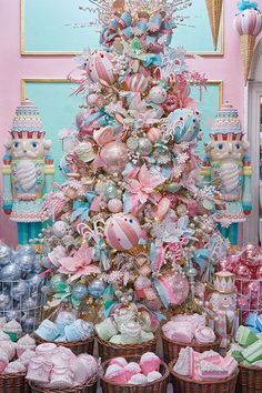 a christmas tree decorated with pink, blue and white ornaments in baskets on the floor