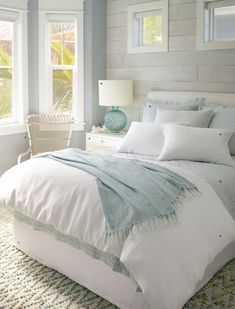 a white bed sitting in a bedroom next to two windows