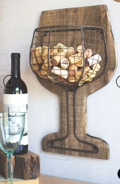 a wine bottle and glass on a table with a wire basket filled with food next to it