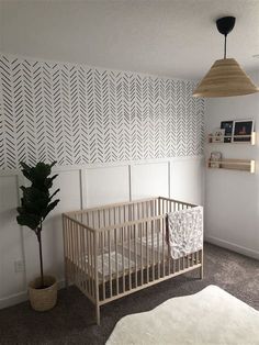 a baby's room with a crib, potted plant and wallpaper