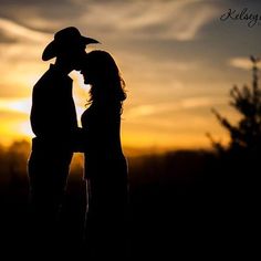 the silhouette of two people kissing in front of a sunset