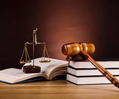 a judge's gavel sitting on top of a book next to an open law book