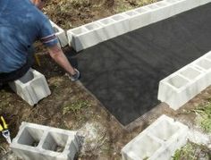 a man laying concrete blocks on the ground