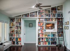 a living room filled with lots of books on top of a book shelf next to a doorway