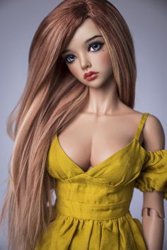 a close up of a doll with long hair wearing a yellow dress and red lipstick