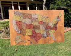 a wooden map of the united states on display in front of a house with green grass