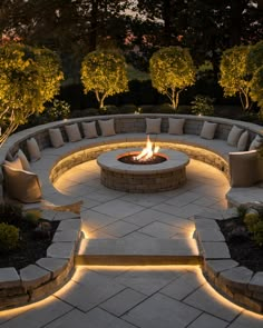 an outdoor fire pit surrounded by stone steps and seating area with lit lights on each side