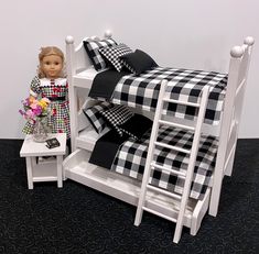 a doll sitting on top of a white bunk bed next to a black and white checkered comforter