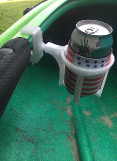 a can of soda sitting in the back of a green car with an american flag design on it