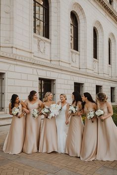 a group of women standing next to each other in front of a white brick building