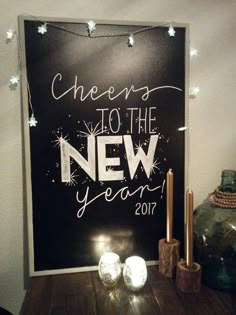 a chalkboard sign that says cheers to the new year on it with lights around it