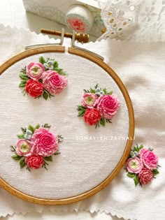 four pink roses are in the middle of a embroidery project