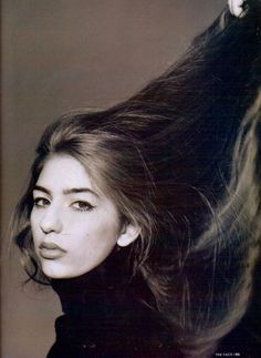 a black and white photo of a woman with her hair blowing in the wind,