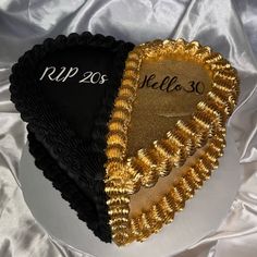 two heart shaped cakes sitting on top of a white table cloth covered in gold and black frosting