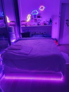 a bed that has some lights on it in the room with purple lighting around it