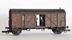 a model train car with two men standing inside the caboose and looking out