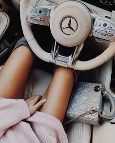 a woman sitting in the driver's seat of a car with her hands on the steering wheel