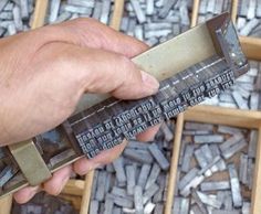 a person holding a ruler in their hand over some type of metal letters that are stacked on top of each other